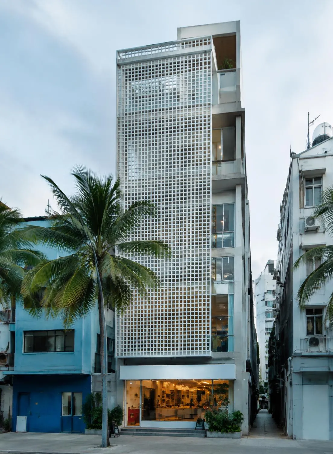 Slender mixed-use building with a perforated white facade