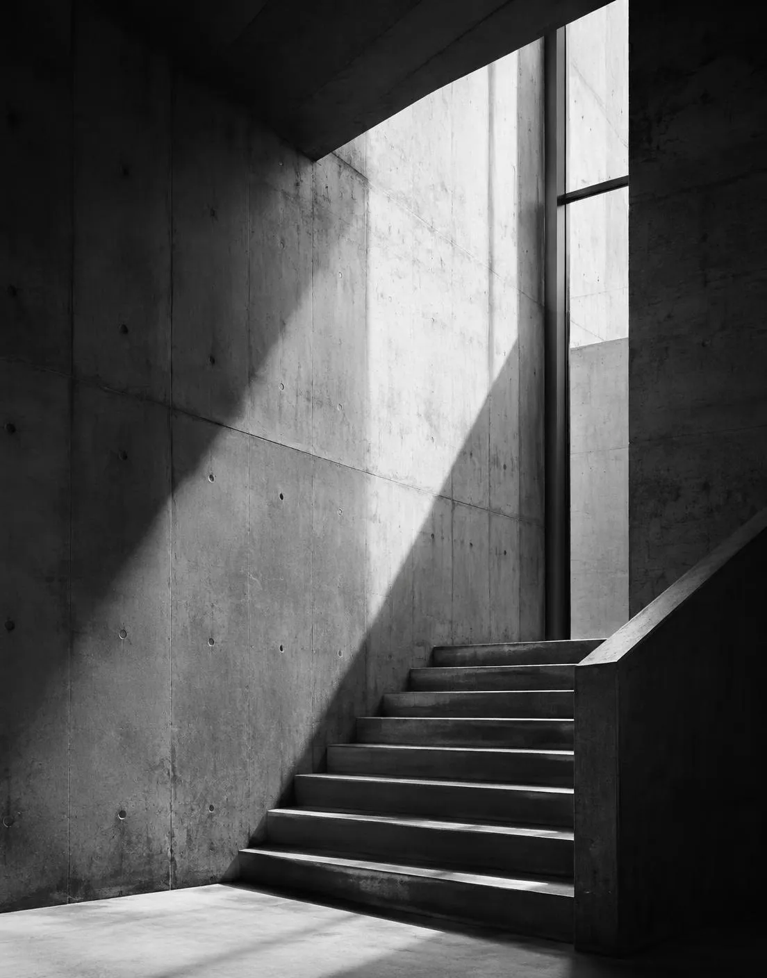 Concrete stair washed by a diagonal shaft of light